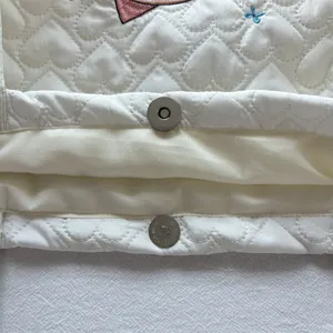 Gewatteerde hart schoudertas detail met magnetische drukknoop en schattig borduurwerk.