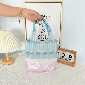 Vue détaillée du sac cabas rayé avec imprimé nœuds, bordure en dentelle et matelassage.