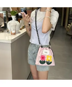 Detailed view of the pink canvas phone bag with cute embroidered flowers and drawstring closure.