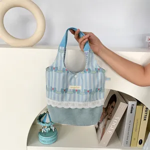 Détail de sac à main en velours côtelé à rayures bleues avec nœud et bordure en dentelle.