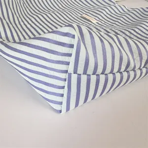 Detail view of a minimalist striped tote bag, showing mint green and purple fabric texture.