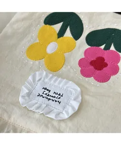 Close-up detail of cute canvas mobile phone bag featuring embroidered felt flowers and ruffled tag.
