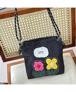 Detail view of black canvas crossbody phone bag featuring cute embroidered colorful flowers and patch.