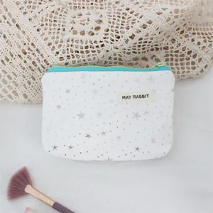 White canvas pouch featuring silver star sequins, detailed view of cosmetic makeup bag.
