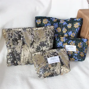 Vista dettagliata di pochette cosmetiche floreali vintage con texture metalliche.