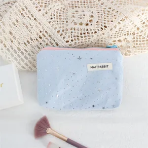 Close-up view of light blue cosmetic pouch featuring silver star sequins and pink zipper.