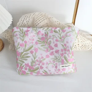 Vista dettagliata della trousse trucchi rosa vintage a fiori con morbido tessuto e etichetta.