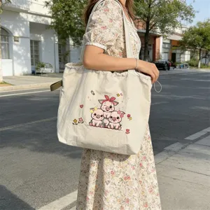 Detalle del bolso tote de lona con bonito bordado de cerdito y correa para el hombro.