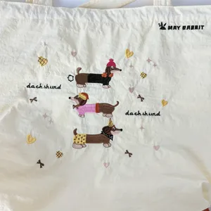 Vista dettagliata di una borsa in tela bianca con simpatici cani bassotto ricamati e cuori.