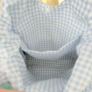 Vue détaillée de l'intérieur et de la poche du sac à main en vichy bleu et blanc.