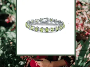 Nahaufnahme des silbernen Tennisarmbands mit ovalen grünen Peridots und glänzenden Steinen.