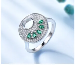 Nahaufnahme eines silbernen Rings mit Pavé-Zirkonia und birnenförmigen grünen Steinen.