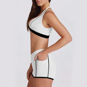 Detailweergave van witte sportbh en short set met zwarte contrasterende rand en zak.