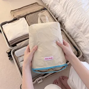 Travel shoe storage bag detail view, portable zip organizer pouch in beige with blue zipper detail.