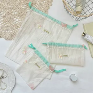 Organza opbergtas detail getoond met delicate bloemborduursels en een handig trekkoord.