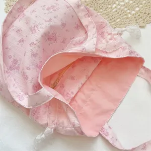 Detailansicht der rosa Beuteltasche mit Blumenmuster, Innenfutter, Reißverschlusstasche und Spitze.