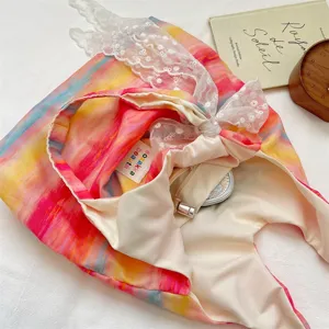 Close up of colorful tie dye canvas bag detail with white lace trim and inner label.