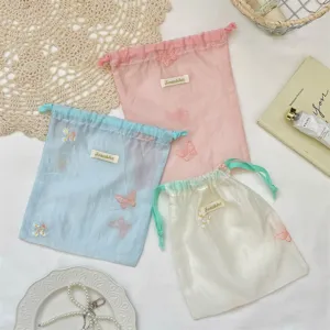 Detail van de organza opbergtas in macaronkleur, schattig bloemenborduurwerk met trekkoordsluiting.
