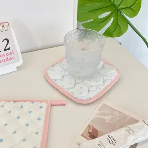 Close-up detail of soft quilted fabric coaster with cute heart pattern, desktop decor setup.