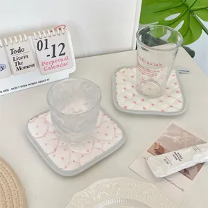 Korean cream style polka dot quilted coaster, soft insulated fabric pad for coffee and tea cups on desktop.
