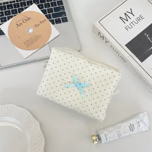 Vista dettagliata della trousse per cosmetici a pois in tessuto con fiocco blu.
