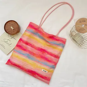Colorful tie-dye canvas tote bag detail shot showing vibrant watercolor stripes and pink straps.