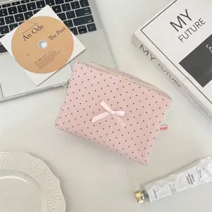 Dettaglio di trousse per cosmetici rosa a pois con grazioso fiocco su sfondo da scrivania estetico.