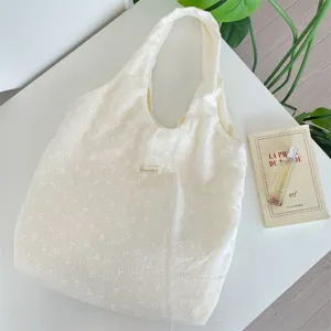 Korean style floral embroidered hollow texture hobo bag detail shot, elegant fabric tote bag.