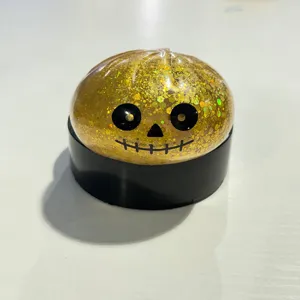 Nahaufnahme eines goldenen Halloween-Glitzer-Kürbis-Quetschspielzeugs mit Totenkopfgesicht