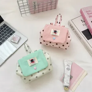 Cute polka dot cosmetic bag with contrast flap and portable handle for daily makeup storage.