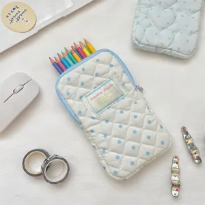 Vue détaillée de la trousse matelassée mignonne à pois bleus et crayons colorés.