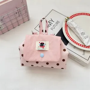 Pink polka dot cosmetic bag with cute cartoon cloth label, handy handheld storage pouch.