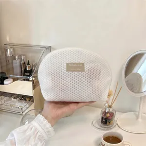 Detailansicht der weißen Netzkosmetiktasche mit strukturiertem Gewebe und Markenaufnäher.