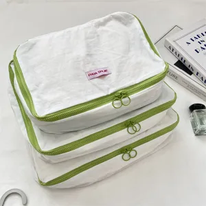 Detailansicht weisser Packtaschen mit gruenen Reissverschluessen, stilvoller Reise-Organizer.