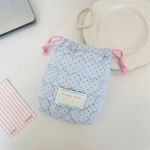 Gros plan du sac cordon matelassé bleu avec motif cœur, montrant les détails de texture.