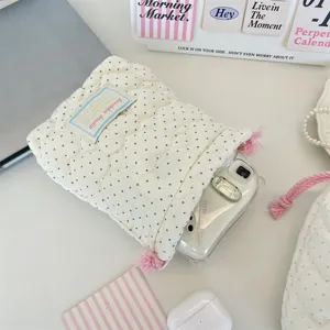 Pochette de rangement matelassée à pois roses avec cordon pour cosmétiques de voyage.