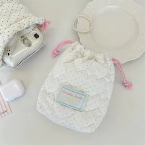 Détail de pochette de rangement matelassée, sac de maquillage rembourré avec cordons roses.