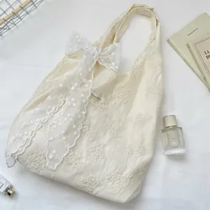 Detailed view of cream embroidered floral tote bag with large lace bow, aesthetic canvas handbag.