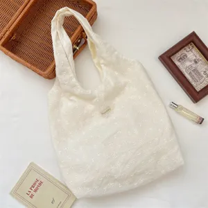 Detailed shot of Korean floral embroidered hobo bag, delicate hollow-out texture fabric.