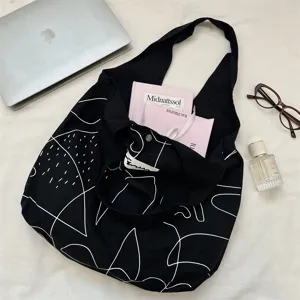 Minimalistische zwarte canvas shopper tas met witte abstracte lijnen en grote capaciteit.