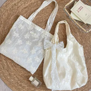 Detailed view of embroidered floral canvas tote bag with delicate lace bow and aesthetic design.
