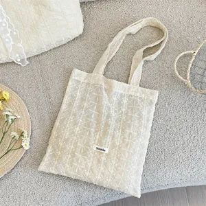 Beige lace embroidered tote bag detail view, soft fabric with delicate floral pattern design.