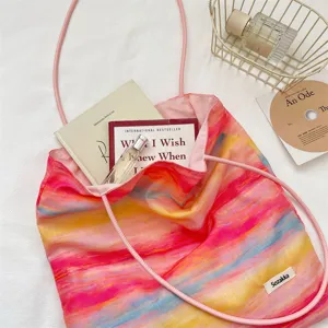 Detail view of the colorful tie-dye canvas tote bag with pink straps and lifestyle props.