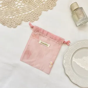 Roze organza opbergtas met trekkoord, schattige vlinder- en madeliefjesborduurwerk details.