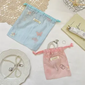 Detailopname van pastelkleurige organza opbergzakjes met prachtige bloemenborduurwerk.