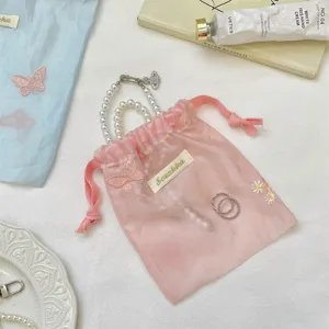 Roze organza trekkoord sieradenzakje met delicate vlinderborduurwerk en parelketting set.