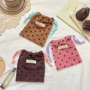 Velvet polka dot drawstring pouch with contrast cords, ideal for travel jewelry storage.
