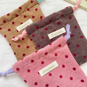 Close-up of portable velvet polka dot drawstring pouches featuring vibrant contrast cords.