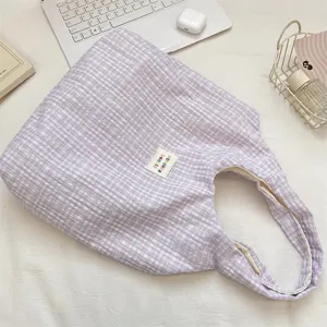 Gedetailleerd overzicht van de paarse ruitjes canvas shopper met stofstructuur en merklabel.