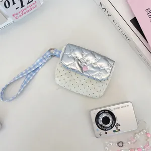 Detailansicht der gesteppten Handgelenktasche mit Punkten, silberner Klappe und Herzdruckknopf.